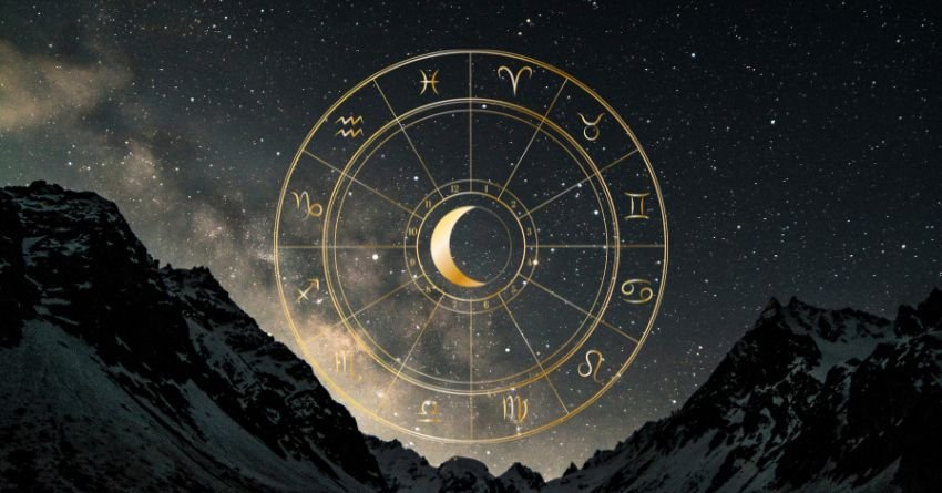 Mystical night sky with a crescent moon and zodiac wheel above a mountain landscape
