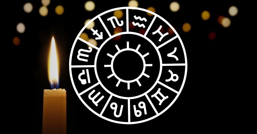 Zodiac wheel with zodiac signs and a candle on a dark background