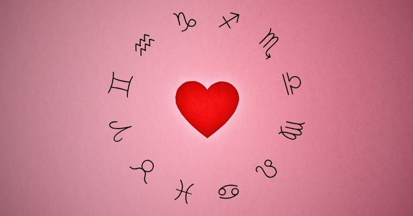 Red heart surrounded by zodiac symbols on a soft pink background